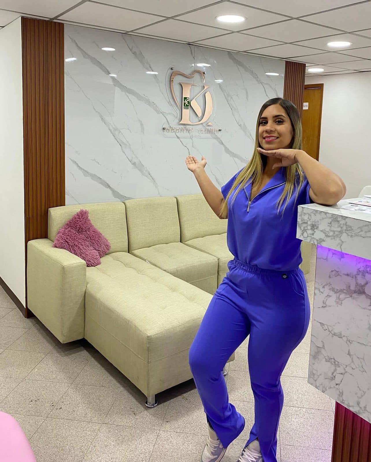 Recepción de K.D Odonto Clinic: sofá, mostrador de mármol iluminado y el logo KD en la pared